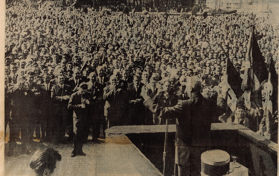 Coupure de presse illustrée d'une photographie sur laquelle on voit le général de Gaulle de dos, face à la foule et aux journalistes. Des drapeaux sont installés à proximité de la tribune. En-dessous, la légende suivante : "Le général de Gaulle prend la parole sur le perron de l'hôtel de ville de Calais, devant une foule considérable".