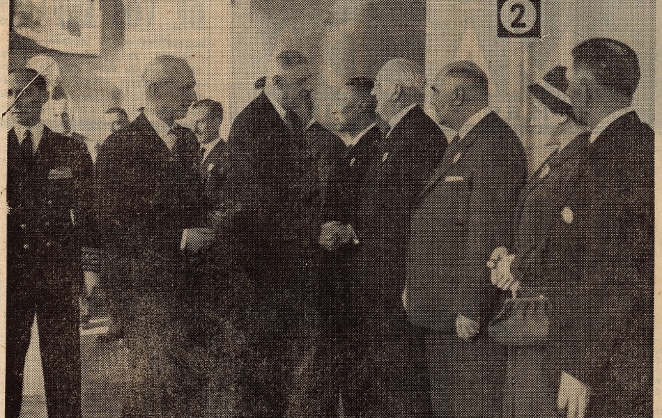 Photographie de presse sur laquelle on voit le général serrant la main de plusieurs personnes qui l’attendent en rang. Le maire de Saint-Omer est à ses côtés.