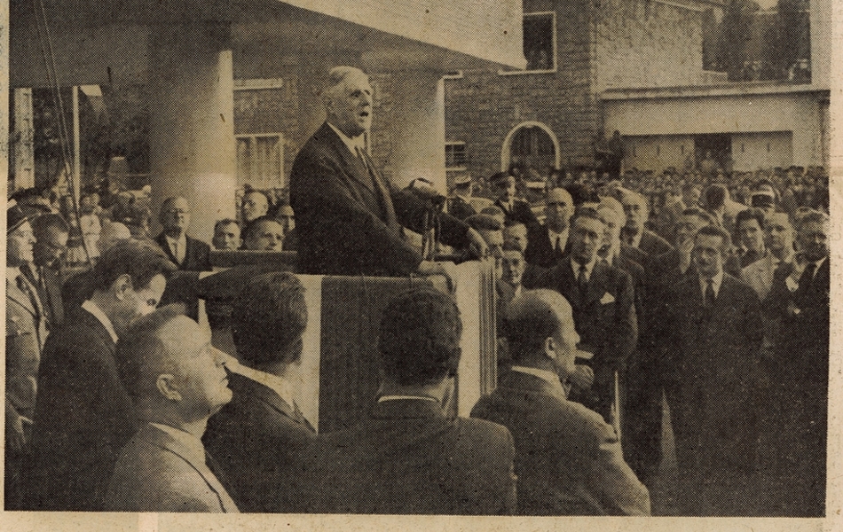 Photographie de presse sur laquelle on voit le général debout dans une petite tribune installée sur la place, entouré par la foule. Il a les mains posées sur la tribune. En-dessous, la légende suivante : "le général prononçant son discours devant l'hôtel de ville de Saint-Pol".