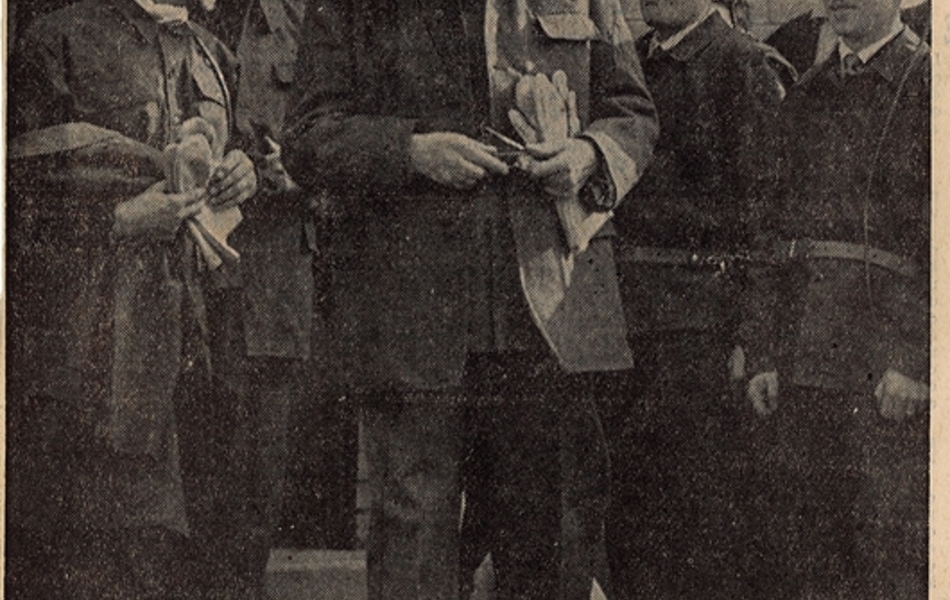 Photographie de presse sur laquelle on voit le général de Gaulle, habillé en mineur et casque sur la tête, entouré d’ouvriers. En-dessous, la légende suivante : "le président de Gaulle, au moment de descendre dans le puits d'Haillicourt, vient de revêtir la tenue réglementaire des mineurs. À sa droite, le ministre des Travaux publics, Monsieur Robert Buron".