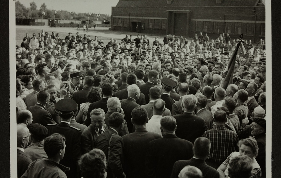 Vue en plongée sur la foule des employés de l'Usine des "Filés de Calais" qui entoure Le Général De Gaulle, Président de la République française, suite à la visite des bâtiments, le 24 septembre 1959.