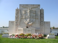 Monument aux morts en pierre blanche, fleuri.