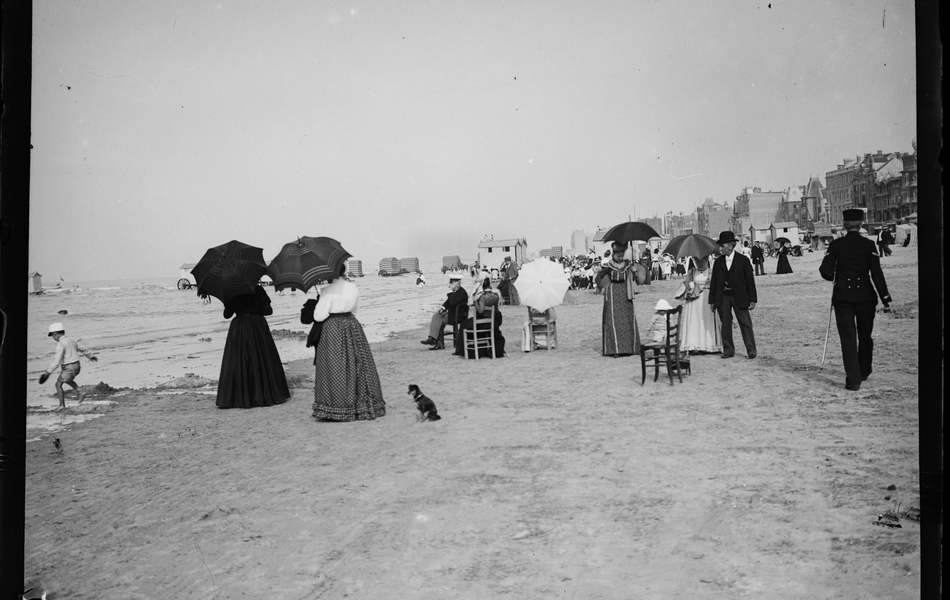 Photographie noir et blanc montrant une plage sur laquelle se trouvent des estivants.
