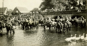 Photographie représentant des cavaliers sur leurs montures en train de s'abreuver dans une rivière, en contrebas d'un pont.