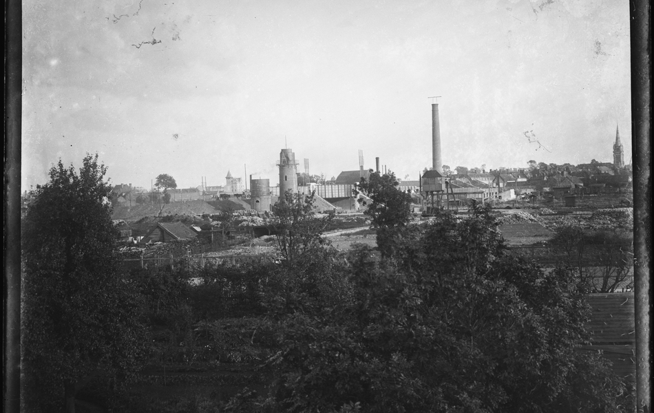 Photographie noir et blanc montrant à l'arrière plan un complexe industriel.