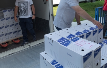 Déchargement de boîtes en carton d'un camion qui sont posées sur un chariot pour entrée dans le dépôt d'archives