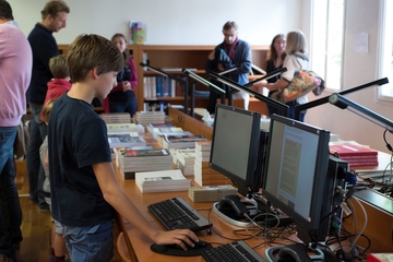 Photographie couleur montrant un enfant derrière un poste informatique.