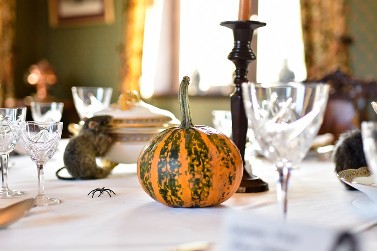 photographie montrant un détail de la table de la salle à manger du château avec au premier plan une citrouille et un rat